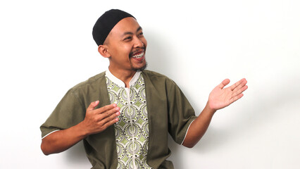 Indonesian Muslim man in koko shirt and peci extends his arms wide in a welcoming gesture, leaving...