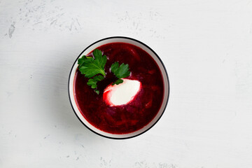 beet soup in a bowl with parsley and sour cream in a bowl on a white background. top view. Bowl of tasty borscht