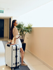 Happy female traveler with suitcase, enjoying her vacation in a modern airport terminal