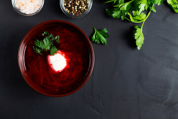 red beet soup with ingredients. delicious borscht with sour cream, green parsley, garlic on the...