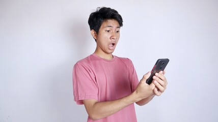Fototapeta premium Asian man in shock with gesture looking and holding smartphone