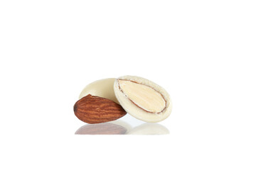 White chocolate covered walnut, whole and half, with reflection on white background.