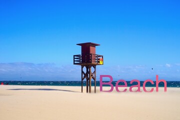 lifeguard tower at a wonderful beach, purple to red beach lettering with shadow next to it,...