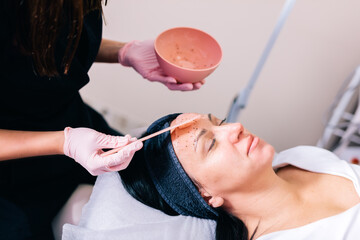 Beautician applying hydrogel mask on her client's face in a beauty salon