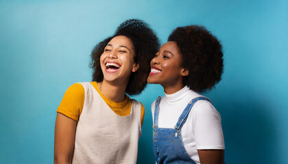 Obraz premium Two friends smiling and laughing; two friends having fun; portrait of two friends laughing; blue background