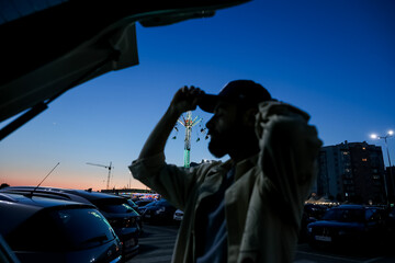 blurred silhouette of a man against the background of evening merry-go-rounds that glow in an...