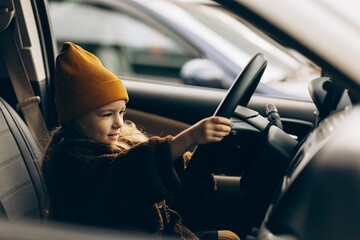 a little girl wearing a yellow hat and jacket poses for a photo while sitting in a white family car