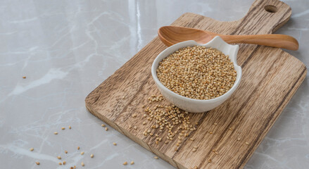 dry ginger seeds on plate on the table. White plate full of sesame grains on cutting board