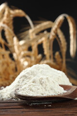 Wheat flour on wooden spoon at wheat ears background