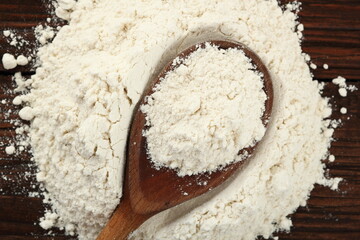 Pile of flour and wooden spoon with wheat flour on plank table. Directly Above.