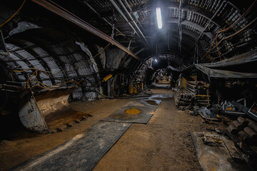 Fototapeta na wymiar Coal mining underground with large machines and in long, dark corridors and tunnels 