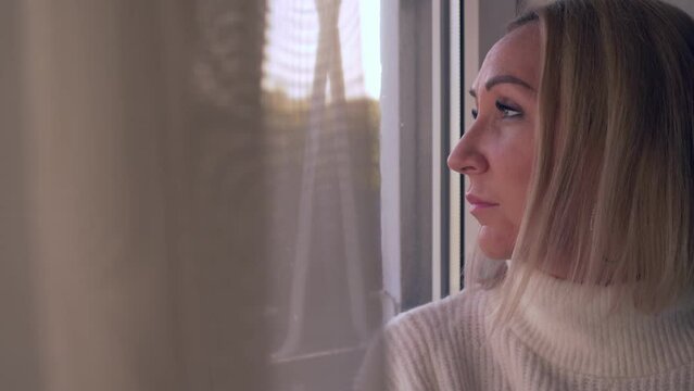 lonely woman looks out the window - sadness, depression, thoughts