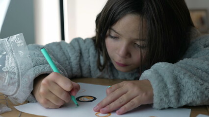 Concentrated Little girl drawing on paper with coloring pen. Creative child engaged in artistic play by herself