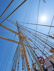 Sailing, ship and mast outdoor with rope for travel, journey and low angle of blue sky in summer. Boat, wood pole and vintage schooner vessel on a cruise, rigging and transportation with sunshine
