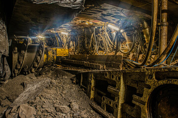 Coal mining underground with large machines and in long, dark corridors and tunnels 