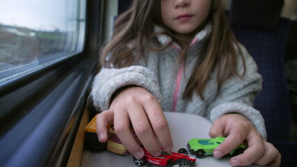 Little Girl Playing with Car Toys on Train, 8 year old kid Engaged in Play by Window while commuting
