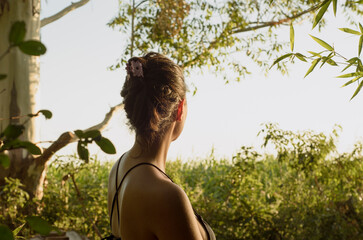 Retrato de mujer latina al sol con fondo natural, expresion relajada