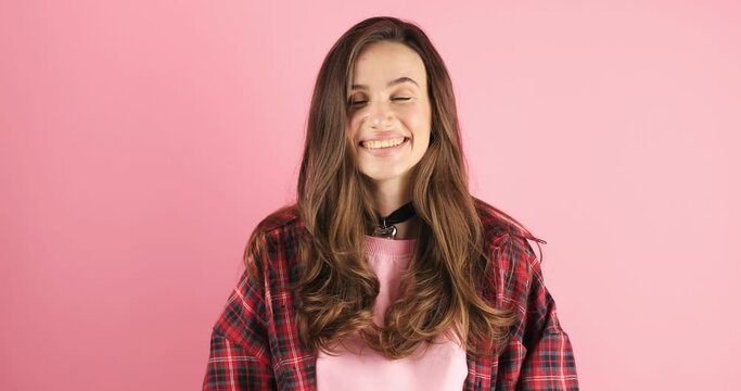 Friendly girl waving hand smiling greeting welcoming over pink background. Cheerful pretty woman smiling wave good bye gesture and look happy. Woman wear red plaid shirt.