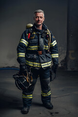 full-length portrait of a firefighter on a dark background with copy space