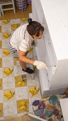 Young woman restoring and painting some old furniture inside her home