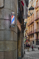 A classic barber pole with illuminated red, white and blue stripes, mounted on a stone wall on a...