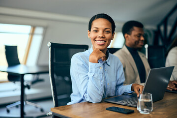 Portrait of a smiling black businesswoman, posing for the camera while having a meeting.