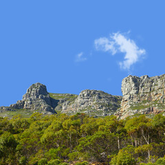 Mountains, sunshine and blue sky with nature, clouds and stone with landscape and environment. Empty, rock and grass with flowers or countryside with summer and travel with holiday, journey or plants