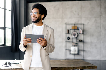 Brazilian professional beams with a genuine smile while holding a tablet in a modern office,...