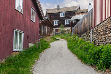 Fototapeta na wymiar In the heart of Roros, this narrow lane meanders past historical wooden structures, their aged facades telling stories of the past. Norway