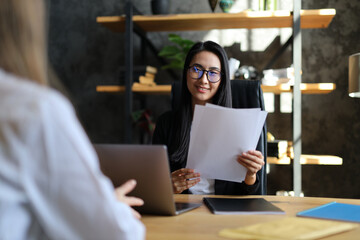 In a business setting, an Asian woman confidently conducts a recruitment interview, fostering a professional atmosphere.