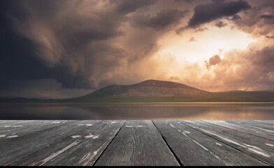Beautiful dark storm clouds over lake, with empty wooden table. Natural template landscape