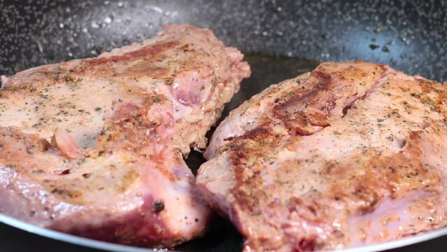 Close up, 4k 60FPS footage of a Delicious juicy pork steak is fried in a pan with smoke. 