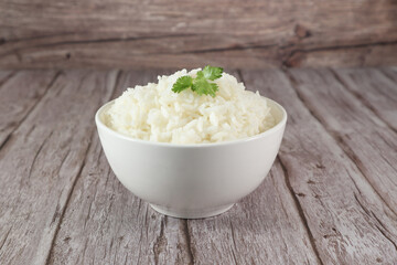 White rice in bowl on wood table. Close up