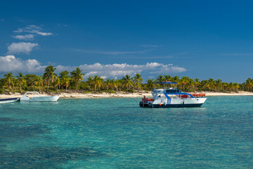 Seascape with crystal clear shallow turquoise ocean water, deep blue sky and tour boat with white...