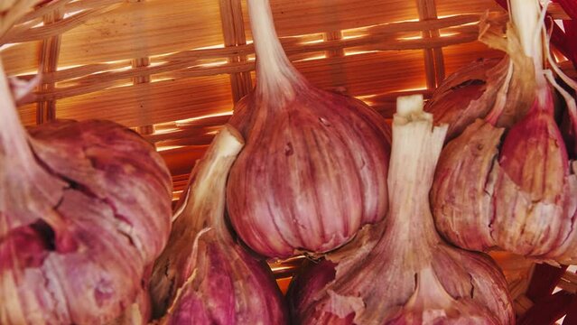 Gyration of old garlic in a straw basket on a wooden table background.