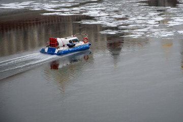 A rescue hovercraft moves along a river covered with broken ice through the reflection of the Kremlin towers on the water. Concept.