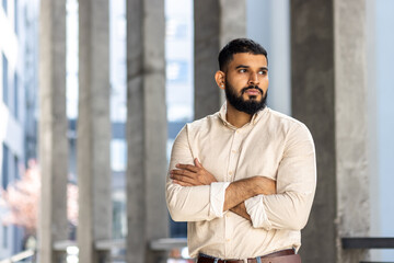 Confident man standing with arms crossed in a modern city environment