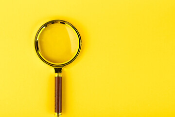 Magnifying glass in a gold frame on a yellow background. Copy space.