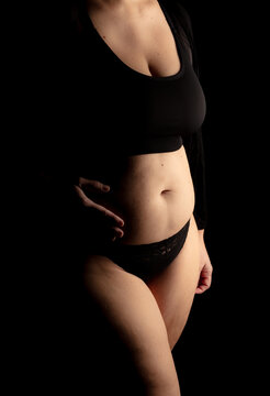 Plus Size model. Woman's body showing belly. Black background