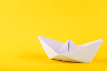 White paper boat on a yellow background. Copy space.