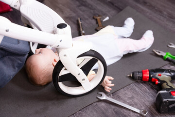 Boy mechanic repairs the suspension of a baby carriage. We repair everything that travels. Humor