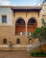 Fototapeta na wymiar Serene courtyard showcases the timeless beauty of Mamluk architecture with high big arches and stonework with welcoming staircase leading to ornate balcony