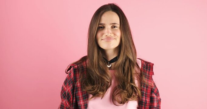 Young pathos woman pointing cheerfully while giving her imaginary money, in front of a pink background. The concept of pouring money without thinking. It makes it rain by throwing money into the air.