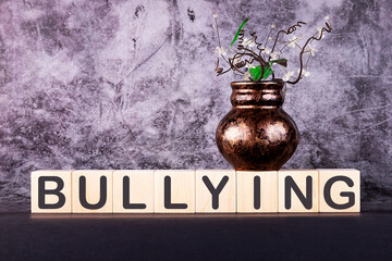 Word BULLYING made with wood building blocks on a gray background