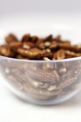 Pecan halves in glass bowl. Isolated on white background.