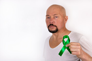 A man holds a green ribbon on the background of his t-shirt. Medical kidney cancer awareness...