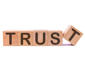 TRUST word concept written on wooden cubes on a light table and light background