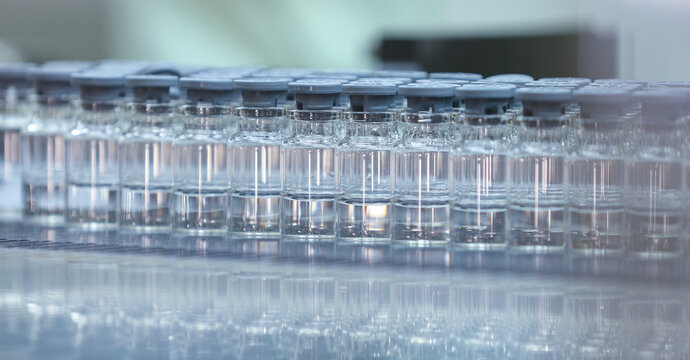 liquid vaccine injection medicine filled glass vials entering into lyophilization chamber for freeze drying process in a medicine manufacturing factory. Lyophiliser with lot of liquid vaccine medicine