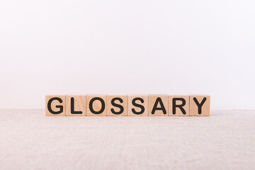 GLOSSARY word concept written on wooden cubes lying on a light table and light background.