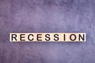 Word RECESSION is made of wooden building blocks lying on a grey background.